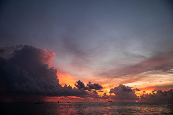 Pink and orange sunset with blue clouds and luxury boats in Pacific Ocean in Maldives Islands
